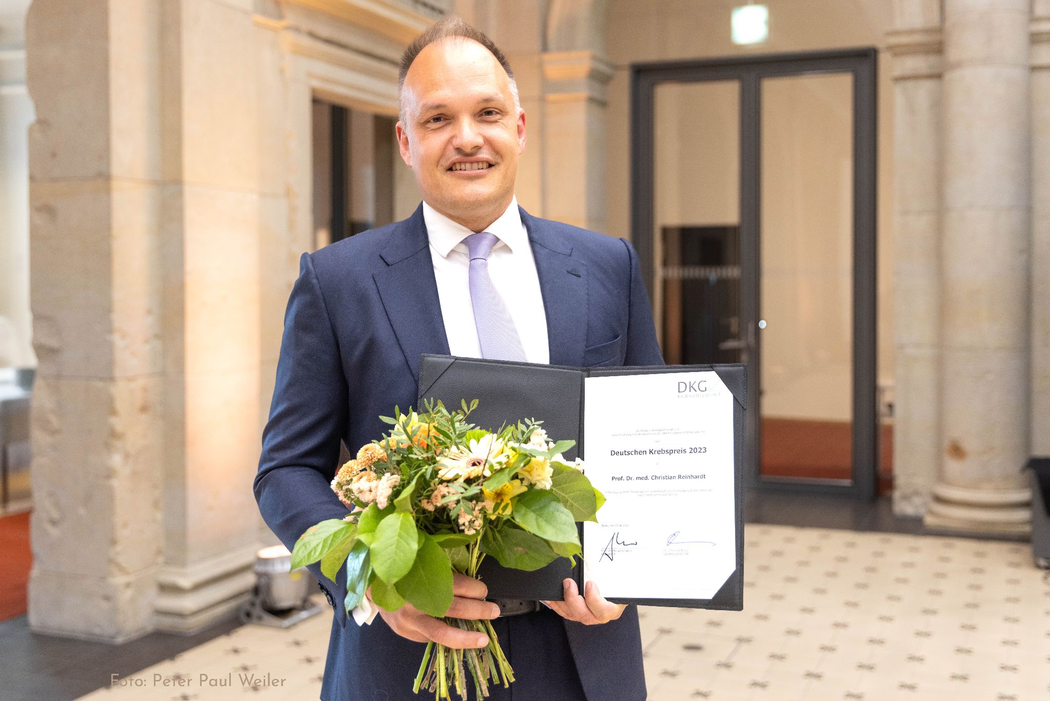 Porträtfoto von Prof. Christian Reinhardt mit der Urkunde.